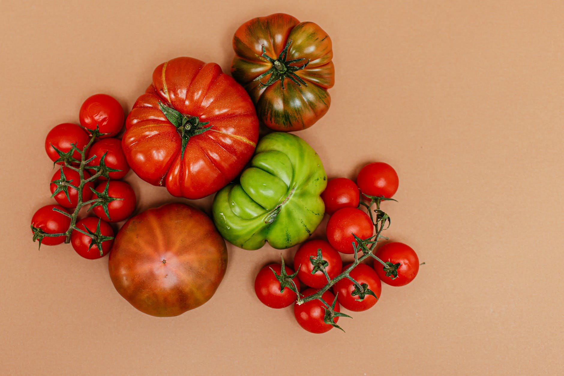 red tomato beside green and orange round fruit